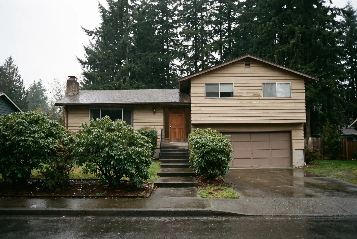 Illustration: a 1970s split-level house on a wet street after a rain shower