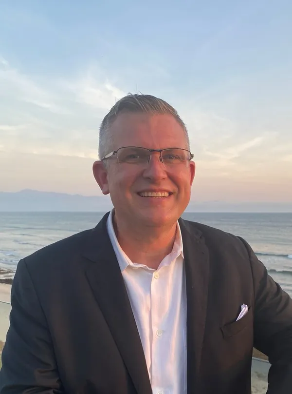 Jason Bryant, owner of Ideal Home Sale, smiling in a dark blazer and white shirt