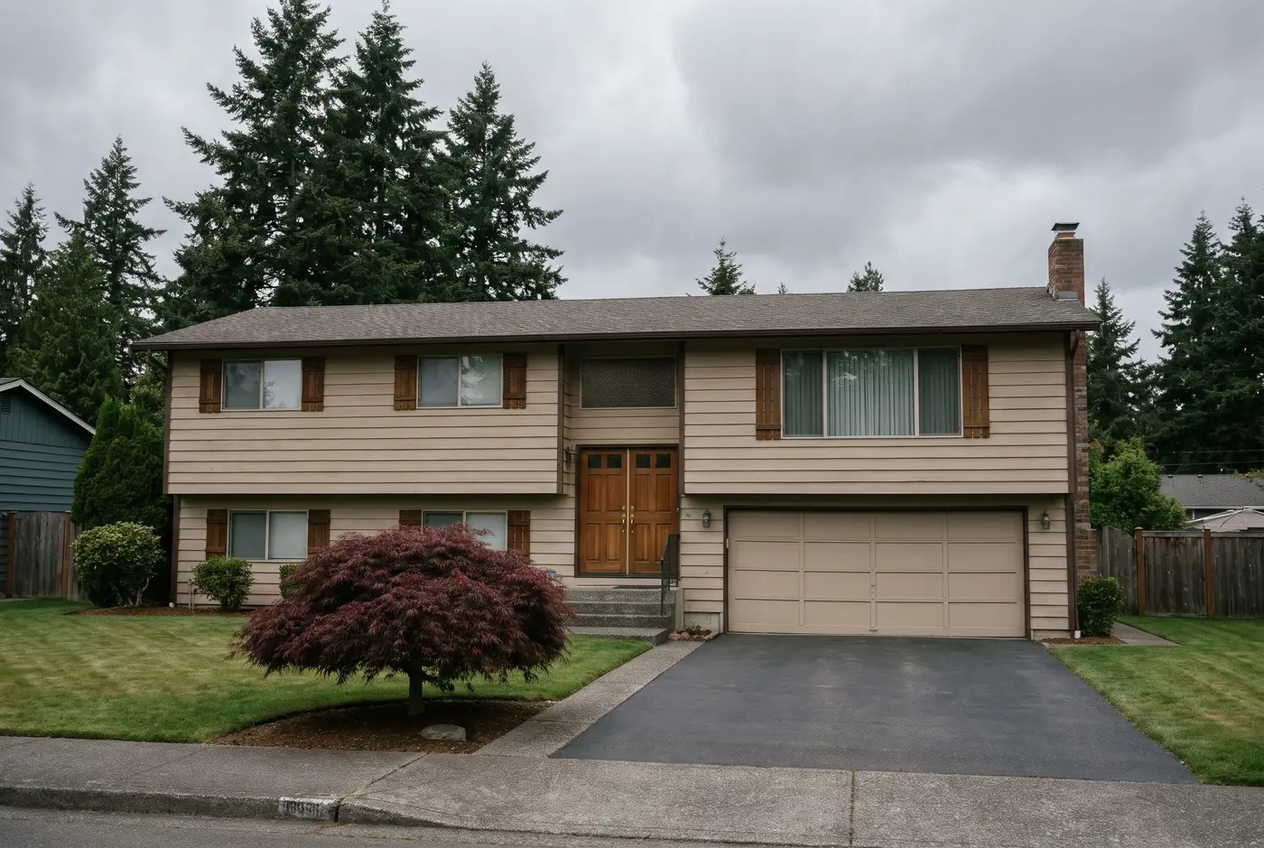 Illustration: a well-kept 1970s split-level house with an empty driveway under tall firs